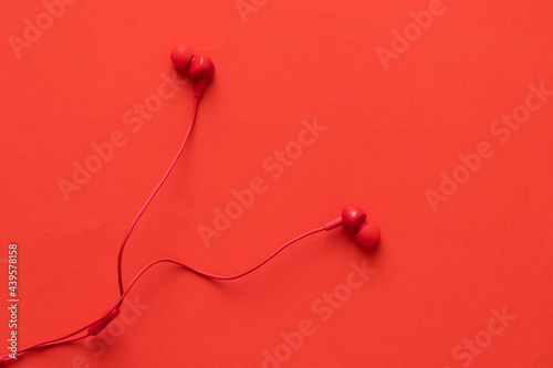 Red headphones with rolled wire, on a red background