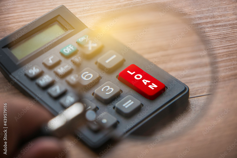 Selective focus of hand holding magnifying glass focusing on a red button of LOAN. Business and finance concept. Selective focus of hand holding magnifying glass focusing on a red button of LOAN. Business and finance concept.