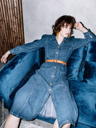 Tired woman in denim dress resting on sofa