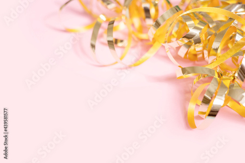 Shiny golden serpentine streamers on pink background with copy space. Top view, flat lay