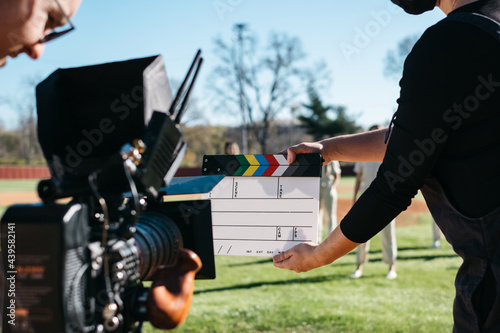 Young woman holds clapboard in front of camera photo