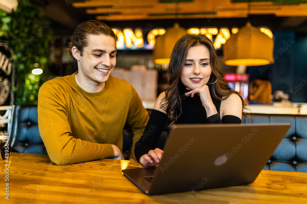Happy couple at coffee shop working at laptop