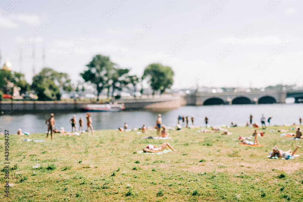 people relax on the grass near the river