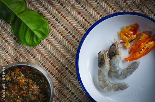 A picture of two fresh prawns that have been peeled and a few other ingredients in the preparation of spicy fresh shrimp paste, such as red chili pepper.