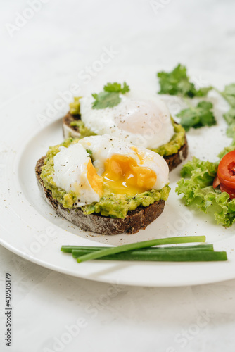 Poached eggs with avocado on sourdough toasts on white background