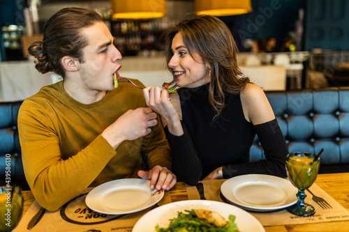 Adult man and woman eating in cafe and smiling to each other