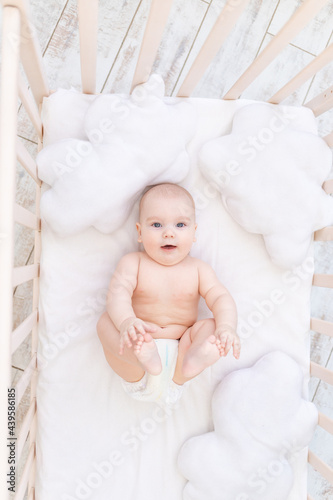 baby boy in the crib in the nursery, cute funny little baby six months, healthy sleep concept