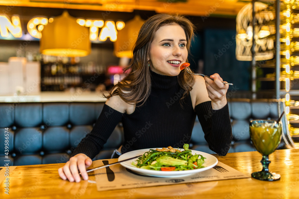 Happy young woman eating lunch in restaurant