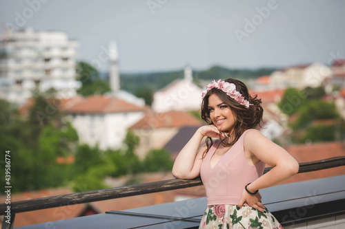 Attractive Caucasian female wearing an elegant floral dress on background of the cityscape photo