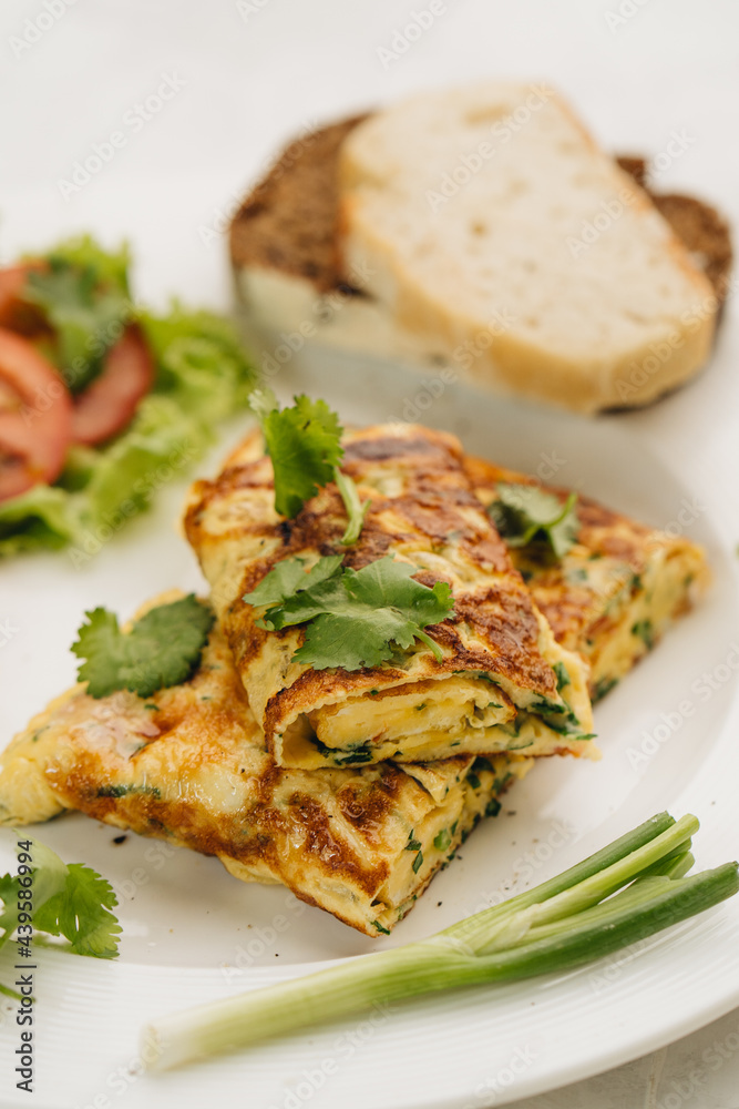 Omelette with tomatoes, bread and coriander on white plate. Omelette with tomatoes, bread and coriander on white plate.