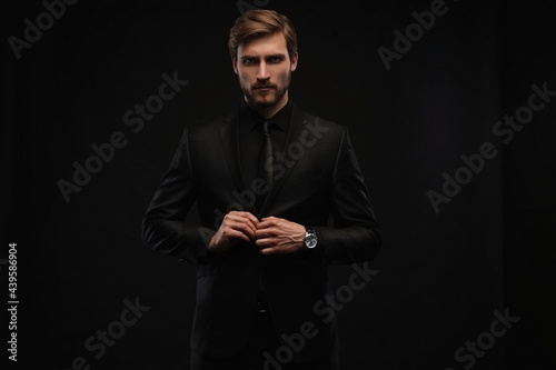 Elegant young handsome man in black suit. Studio fashion portrait