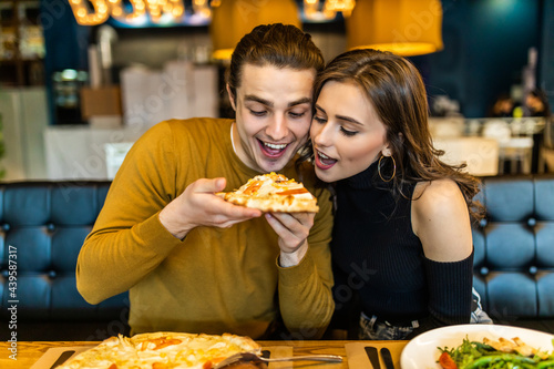 Handsome smiling couple enjoying in pizza, having fun together. Consumerism, food, lifestyle concept