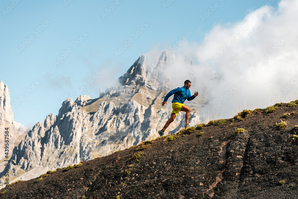 Adult sportsman running uphill in mountains on foggy day Adult sportsman running uphill in mountains on foggy day