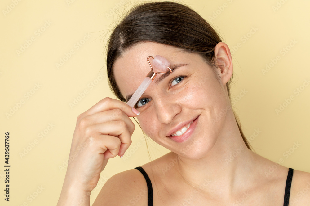 Beauty skincare portrait of a young woman using jade roller Beauty skincare portrait of a young woman using jade roller