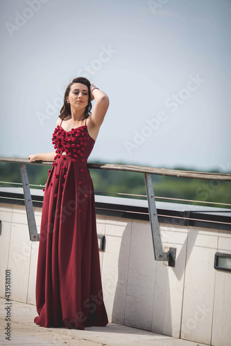 Fototapeta Vertical shot of an elegant caucasian female in a red evening dress with small r