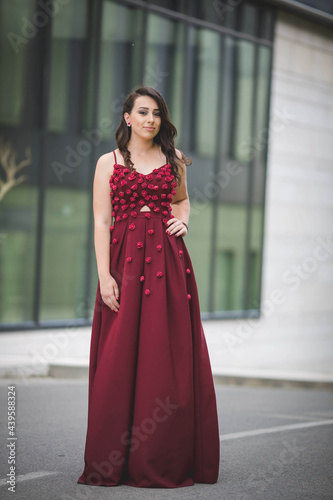 Tela Vertical shot of an elegant caucasian female in a red evening dress with small r