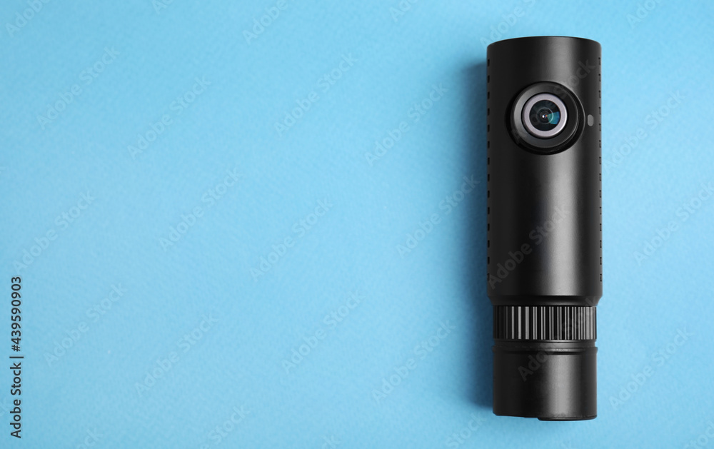 Fototapeta premium Black modern car camera on turquoise background, top view. Space for text