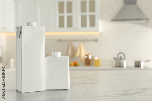Carton boxes of milk on table in kitchen, space for text