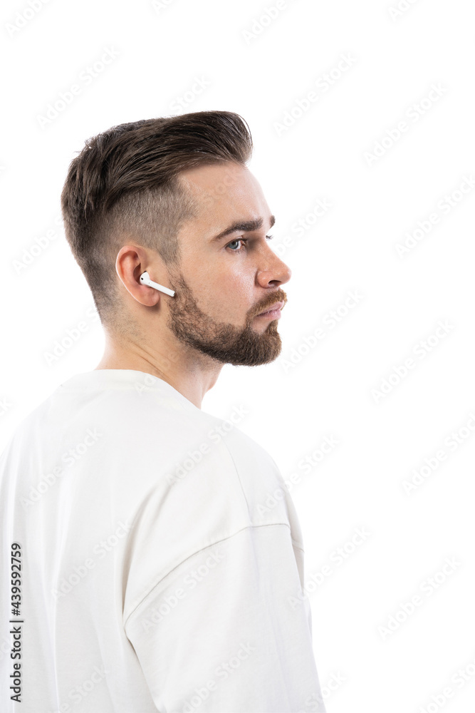Handsome bearded man in white clothes using wireless earbuds on white background Handsome bearded man in white clothes using wireless earbuds on white background