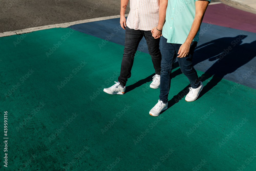 Gay Couple Holds Hands While Walking Across Rainbow Crosswalk Gay Couple Holds Hands While Walking Across Rainbow Crosswalk