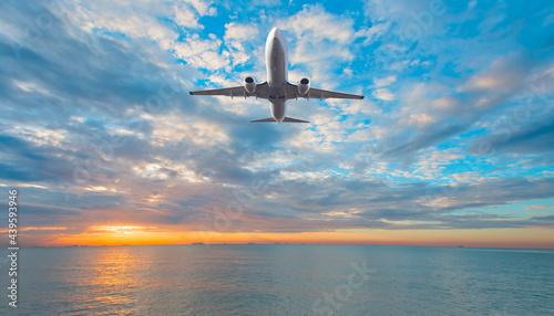 Airplane flying over tropical sea at sunset