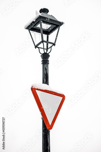 Give way sign on streetlight in city photo