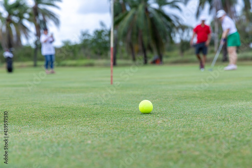 Athletes hit the golf ball into the hole. with supporters around © chaiyapol