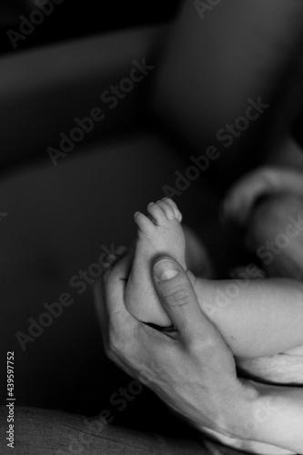 a parent's hand holds their child's little leg © Liya Varkentin