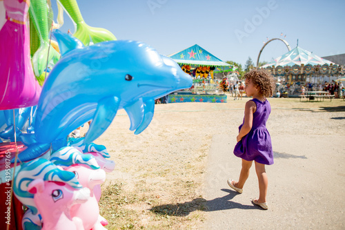 Girl walks past inflatable dolfin at county fair