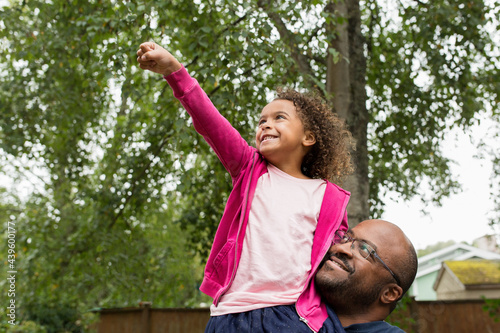 Smilng girl on dad's shoulder raises fist in victory
