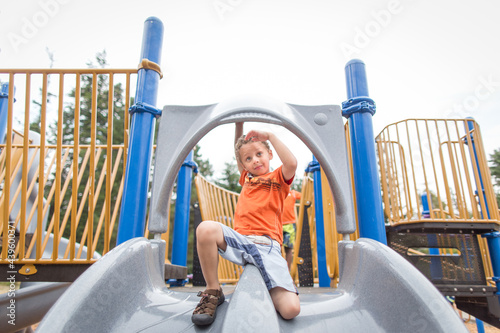 Curly haired boy on playground slide