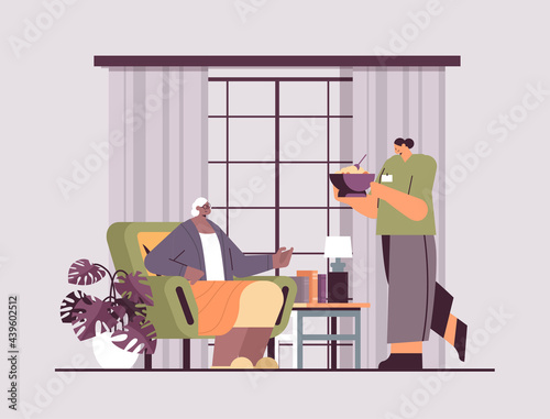 friendly nurse or volunteer bringing food to elderly woman home care services healthcare and social support