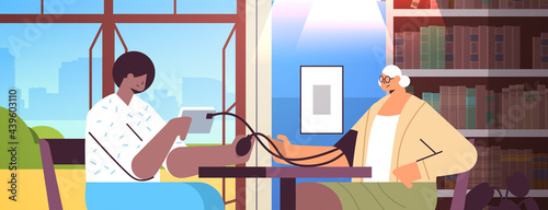 nurse or volunteer checking blood pressure to elderly woman home care services healthcare and social support