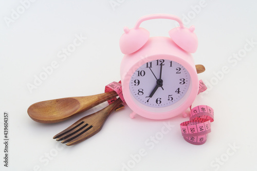 Diet concept. Spoon, fork and measuring tape with alarm clock. photo