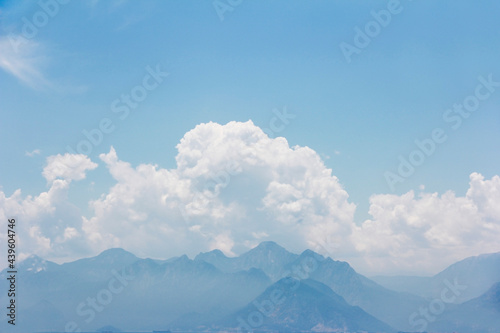 white fluffy clouds, blue sky and mountains