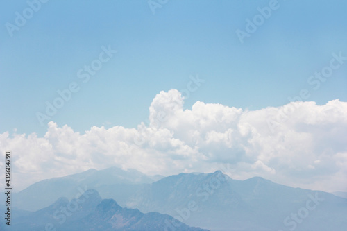 white fluffy clouds, blue sky and mountains © Mari