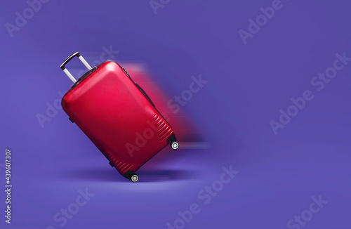 Red suitcase rolling fast on a purpple background