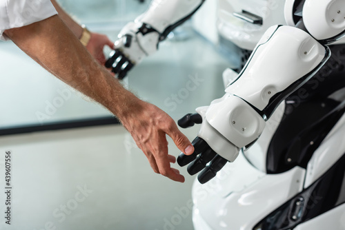 partial view of engineer touching hands of humanoid robot in office