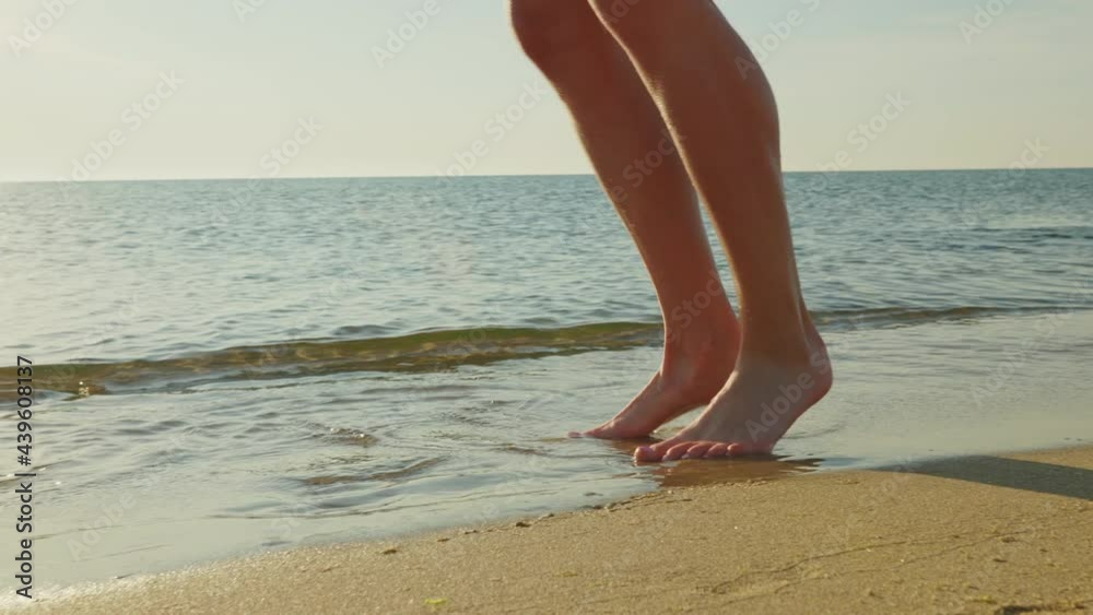 Strong Girl Athlete legs close-up runs on beach on sand splashing water, rejoices against blue sky at dawn summer. Happy beautiful woman walking along sunrise by sea slow motion. Lifestyle. Tourism Strong Girl Athlete legs close-up runs on beach on sand splashing water, rejoices against blue sky at dawn summer. Happy beautiful woman walking along sunrise by sea slow motion. Lifestyle. Tourism