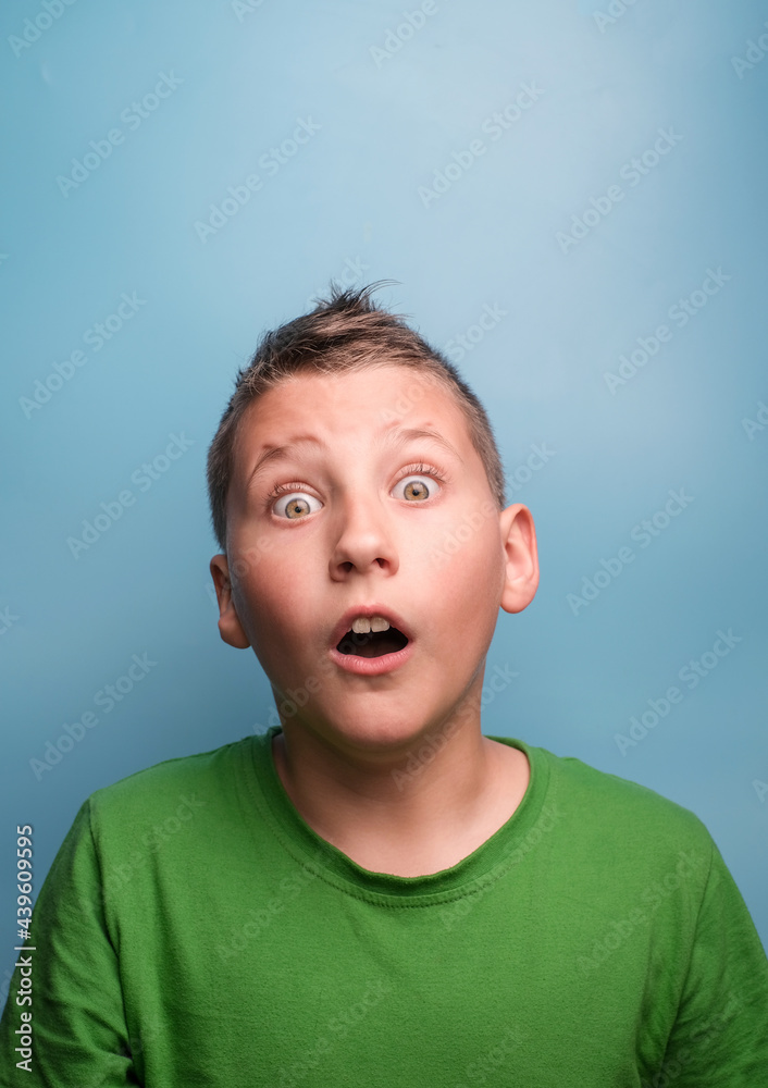 Studio shot of emotional adorable boy with open mouth being surprised and shocked, showing true emotion. Portrait on blue background Studio shot of emotional adorable boy with open mouth being surprised and shocked, showing true emotion. Portrait on blue background