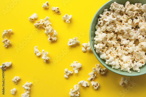 Delicious popcorn in bowl and on yellow background close-up. Food and snack concept.