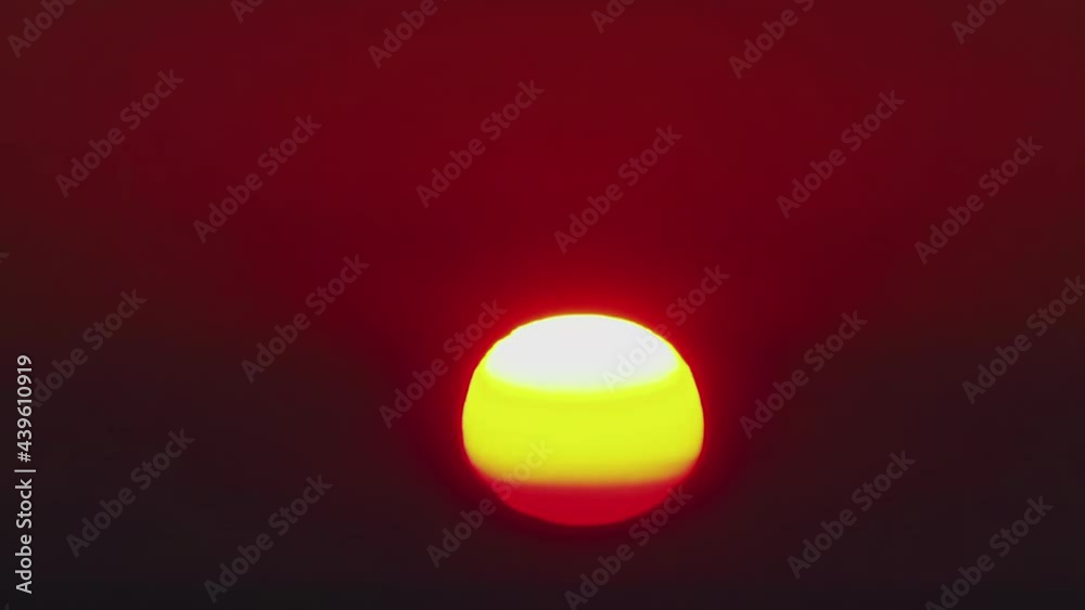 Timelapse, a large sun sets in orange clouds that turn blue. Timelapse, a large sun sets in orange clouds that turn blue.