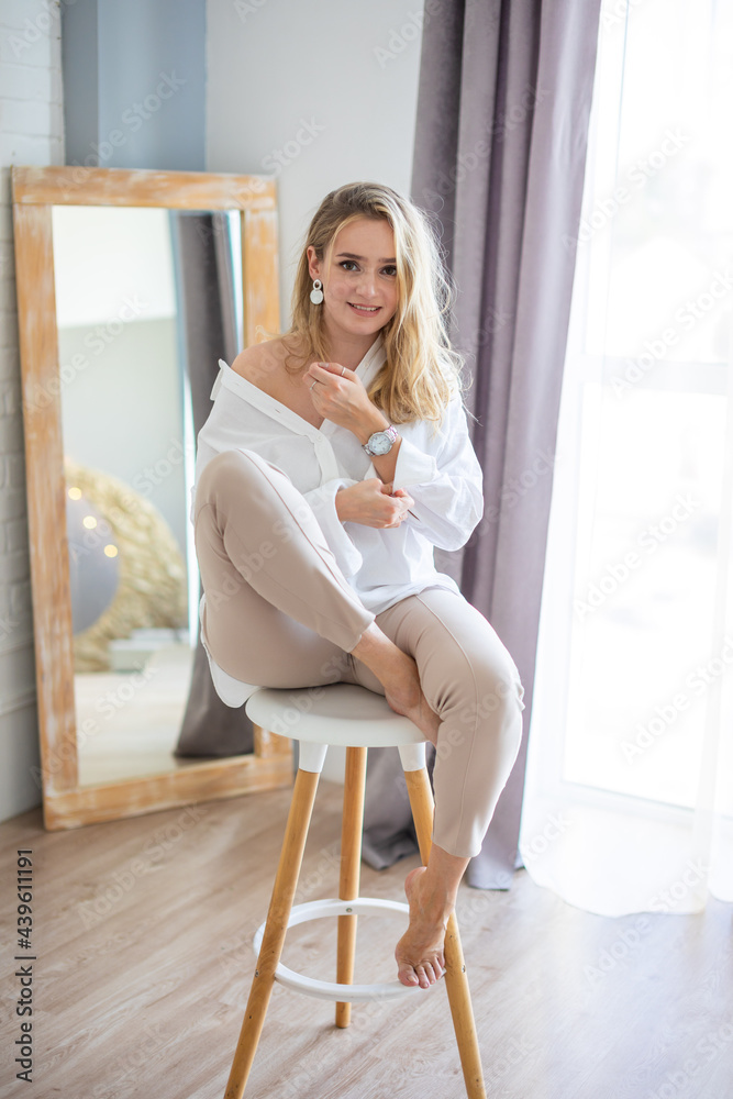 Portrait of a beautiful sensual young woman with blonde hair wearing a white shirt in home interior Portrait of a beautiful sensual young woman with blonde hair wearing a white shirt in home interior