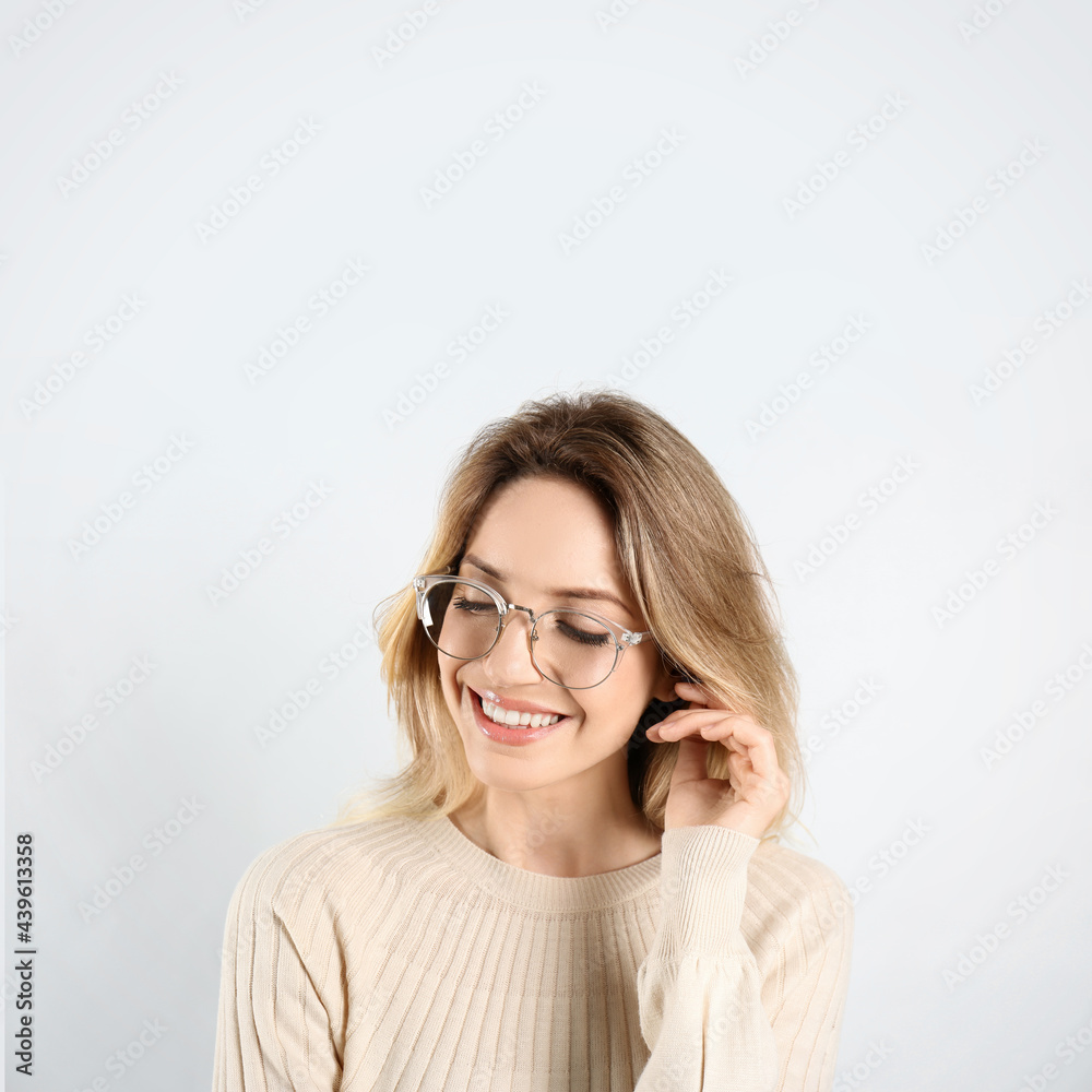 Portrait of happy young woman with beautiful blonde hair and charming smile on light background