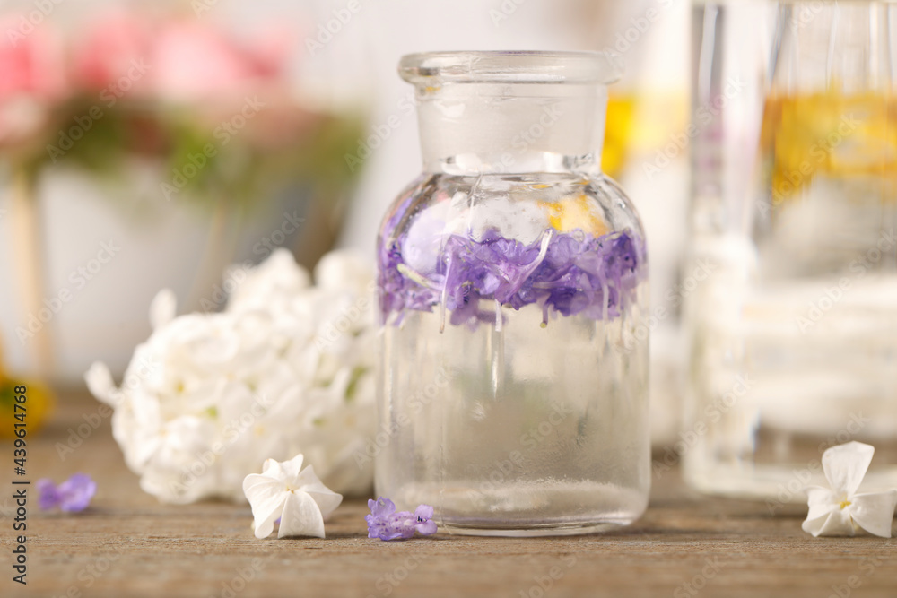 Apothecary bottle with flowers on wooden table in laboratory, closeup. Extracting essential oil for perfumery and cosmetics