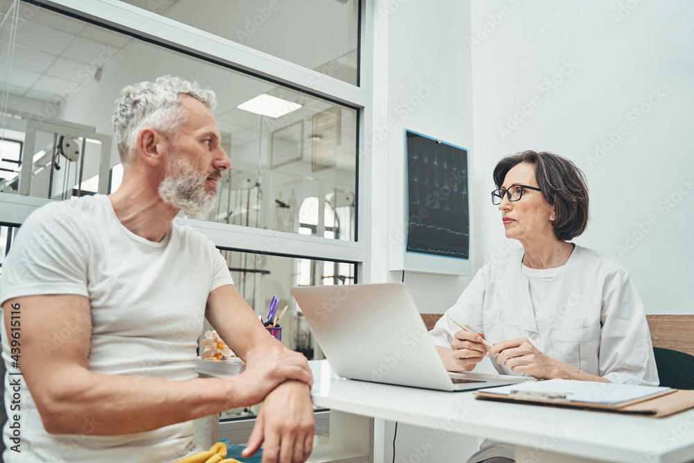 Serious calm vertebrologist receiving a patient in her private office Serious calm vertebrologist receiving a patient in her private office
