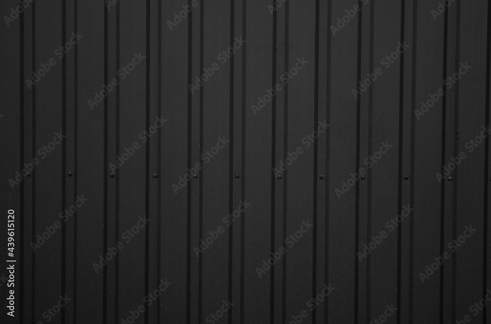 Black corrugated iron sheet used as a facade of a warehouse or factory. Texture of a seamless corrugated zinc sheet metal aluminum facade. Architecture. Metal texture. Black corrugated iron sheet used as a facade of a warehouse or factory. Texture of a seamless corrugated zinc sheet metal aluminum facade. Architecture. Metal texture.