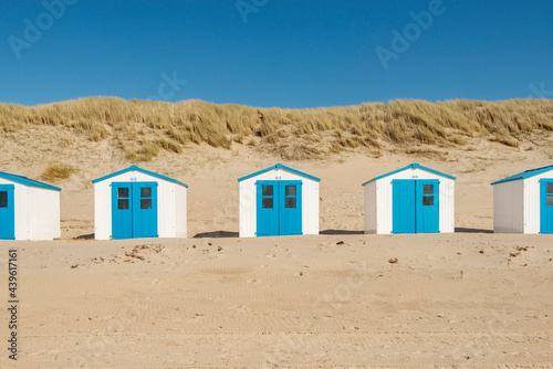 Blue and white beachhouses in the dunes at the beach on the island of Texel in the Netherlands.