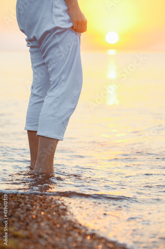 woman legs in sea water. sunset on background © phpetrunina14