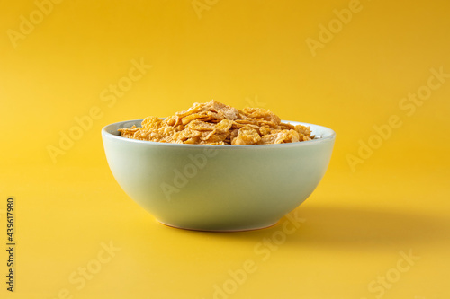 Corn flakes in a blue bowl on yellow background